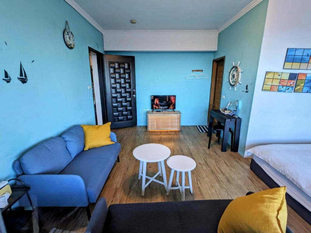 a blue living room with a couch and a table at Blackport Seaview Homestay in Yanliau