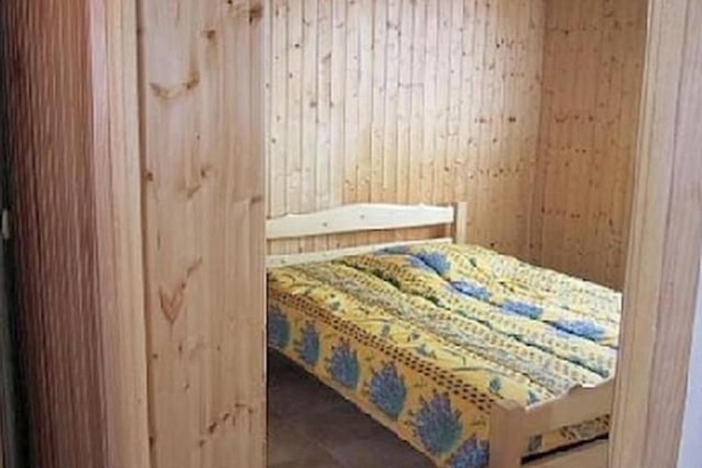 a small bedroom with a bed in a wooden wall at Maison Sur 2 Niveaux in Nance