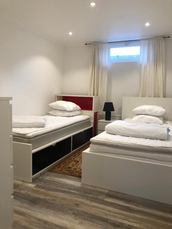 2 łóżka pojedyncze w pokoju z oknem w obiekcie NYRENOVERAD LÄGENHET med egen ingång & nära havet w mieście Sölvesborg