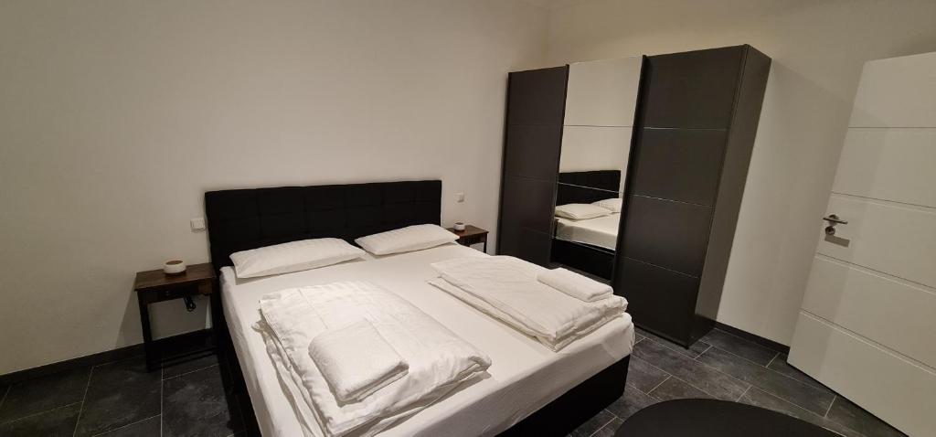 a bedroom with a bed with white sheets and a mirror at RS Zimmervermietung in Euskirchen