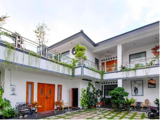 Casa blanca con balcón con plantas en Nexdeco House Homestay Syariah Solo, en Solo