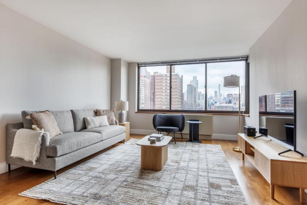 a living room with a couch and a large window at UES 1BR w Gym WD nr Central Park NYC-1296 in New York