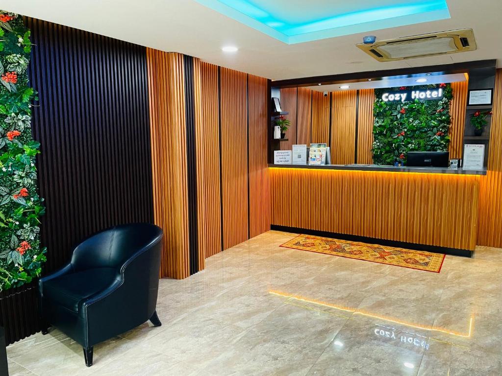 A brightly lit reception desk with a single lounge chair and decorative greenery.