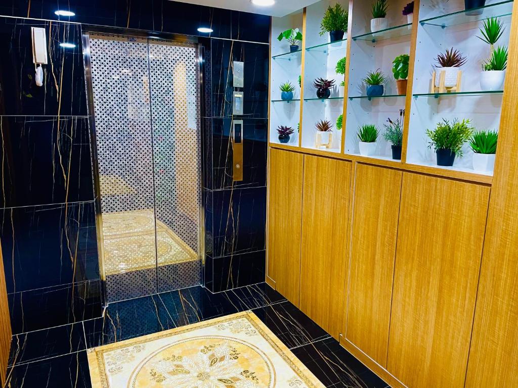 A dark-tiled bathroom with a glass-enclosed shower and built-in plant shelving.