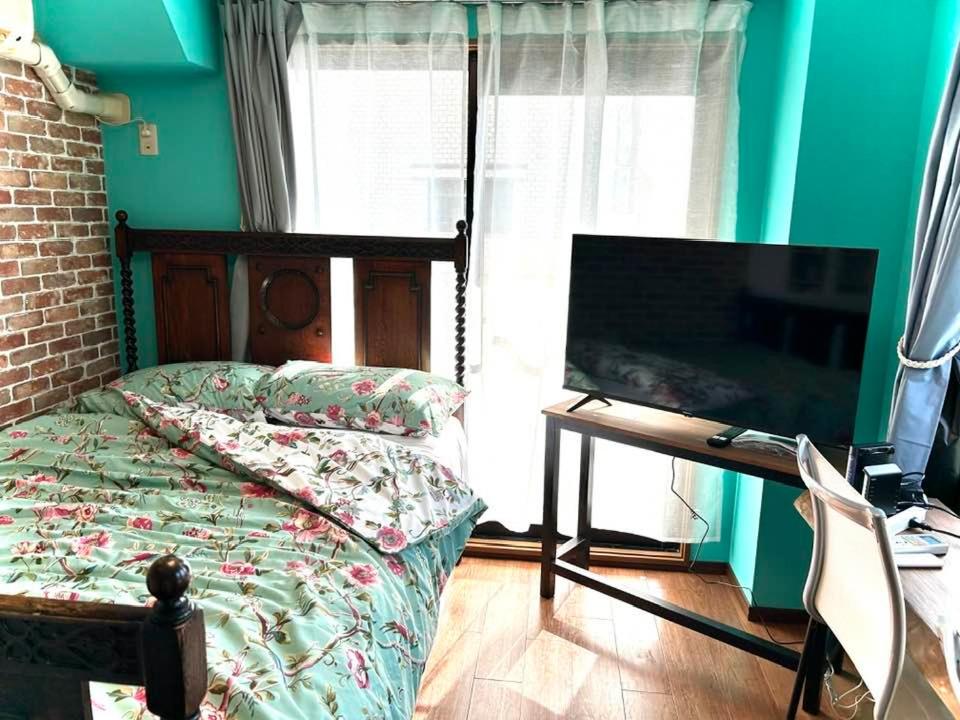 um quarto com uma cama e uma televisão de ecrã plano em ラフォレ１０１　新宿から13分のくつろげるお部屋 em Tóquio