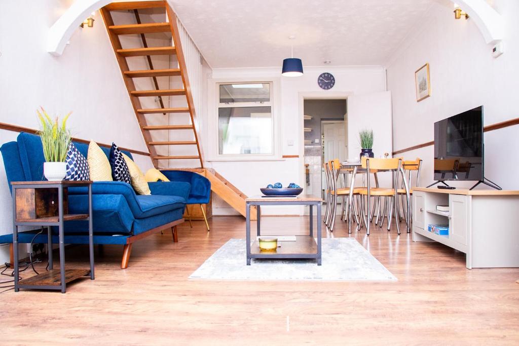 a living room with a blue couch and a staircase at Cosy Windsor Cottage - Free Parking included in Windsor