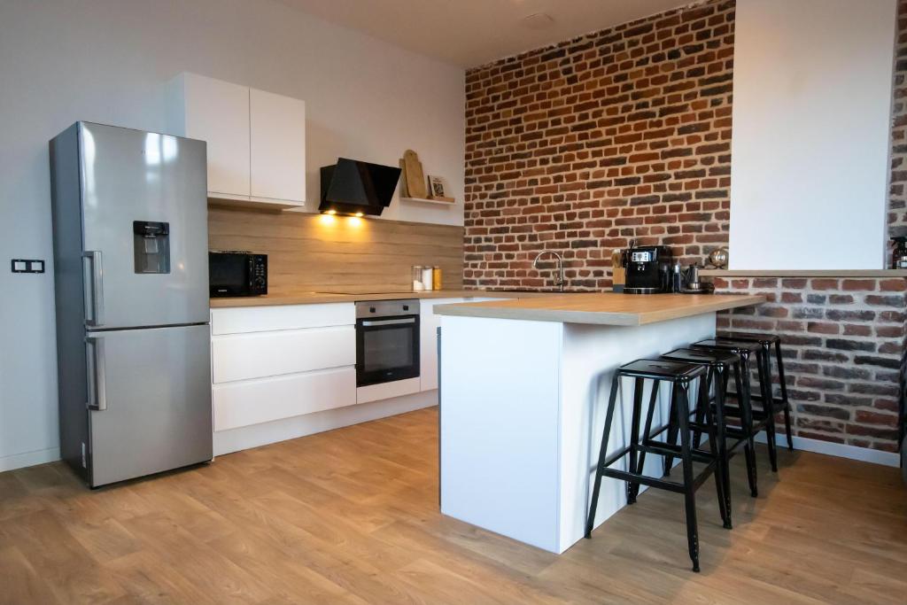 eine Küche mit einem Kühlschrank und einer Ziegelwand in der Unterkunft Appartement Duplex en Centre-Ville de Cambrai - 110m2 in Cambrai