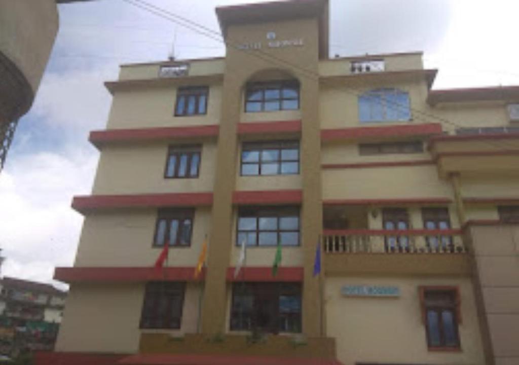 ein hohes Gebäude mit Fenstern und einem Balkon in der Unterkunft Hotel Moomsie Itanagar Arunachal Pradesh in Itānagar