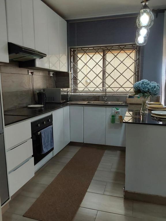 a large kitchen with white cabinets and a window at Rena Apartment in Lilongwe