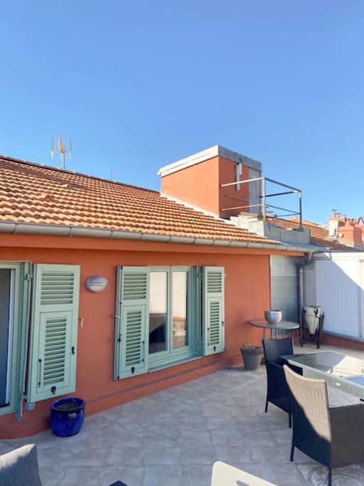 Cette maison orange dispose d'une terrasse avec des chaises et une table. dans l'établissement Place Massena in Nice center - 3 bedrooms top floor, à Nice