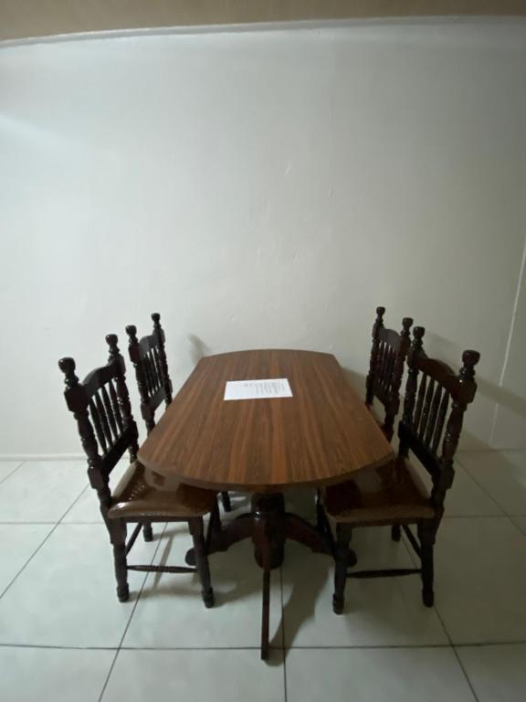 une table en bois avec quatre chaises et un papier sur elle dans l'établissement City Appartementen New Nickerie - 2p, à Nieuw Nickerie