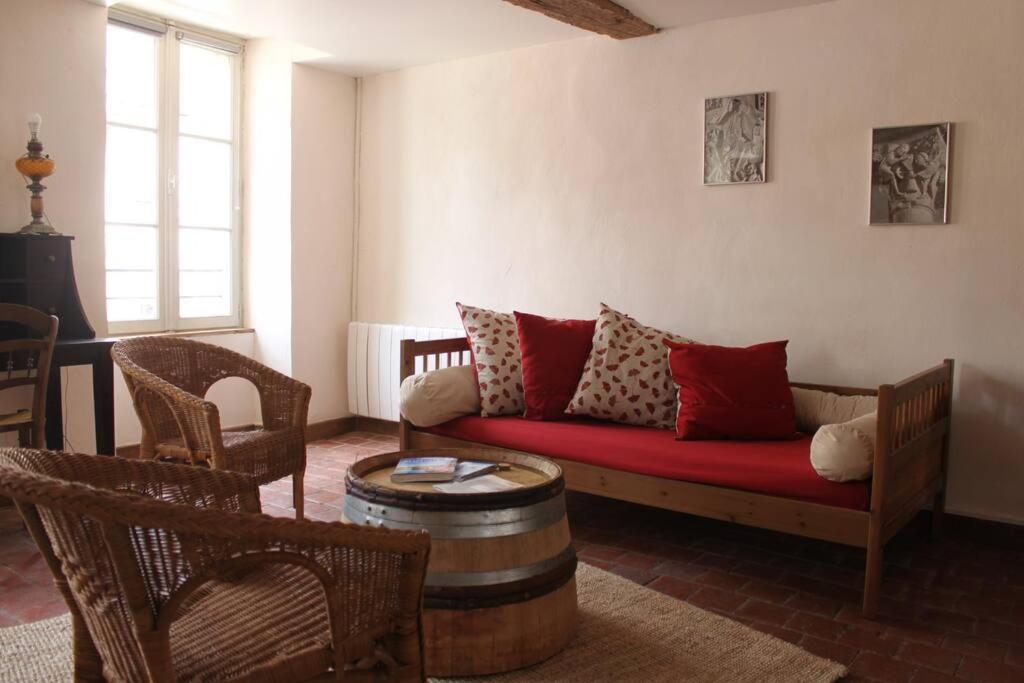 uma sala de estar com um sofá vermelho e cadeiras em Appartement -Le Clos- Cellier de l'abbaye em Vézelay