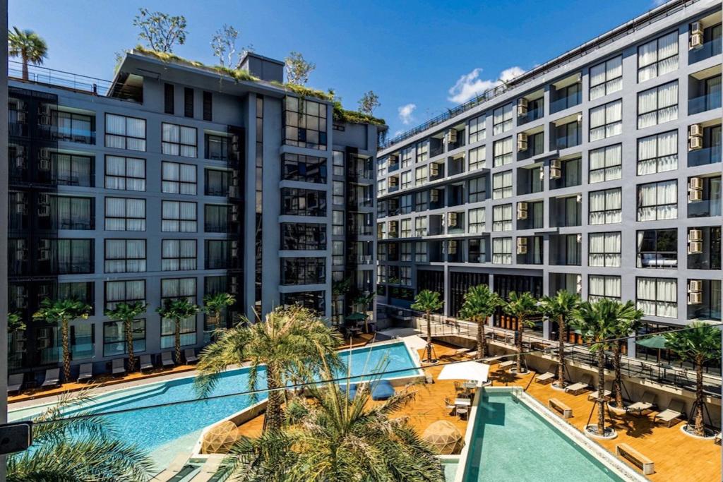 an apartment building with a pool and palm trees at Tropics Kamala 2BR Apartment CTG B605-6 in Kamala Beach
