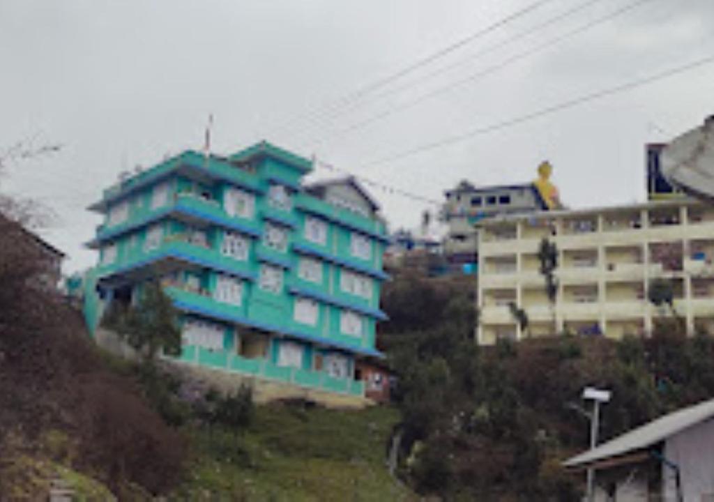 HOTEL MON KYIMOJONG ARUNACHAL PRADESH في تاوانج: مبنى شقق زرقاء على جانب تل
