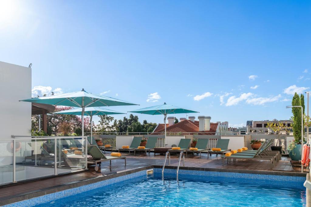 a pool with chairs and umbrellas on top of a building at Hotel Madeira in Funchal