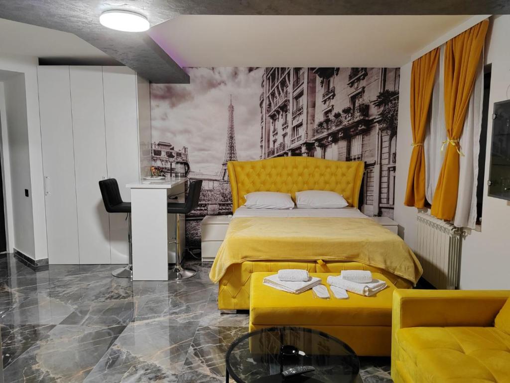 um quarto com uma cama amarela e uma secretária em Hedonic Wellness Apartmani em Niš