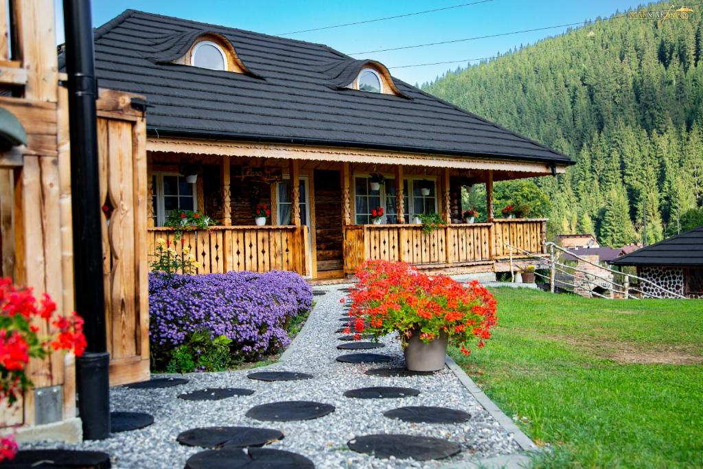 a log cabin with flowers in front of it at La Tarani in Vatra Dornei