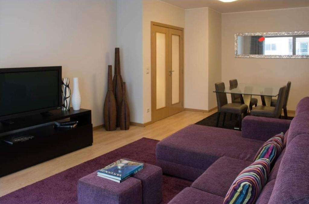 uma sala de estar com um sofá roxo e uma televisão em Apartamento frente ao mar em Lavra