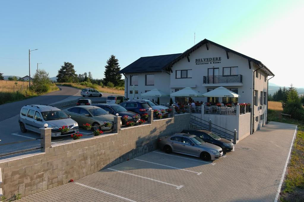um parque de estacionamento com carros estacionados em frente a um edifício em Belvedere Restaurant & Rooms em Topliţa