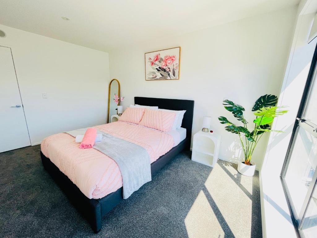a bedroom with a bed with pink sheets and a plant at Walking Distance to Riverside Market & Hospital in Christchurch