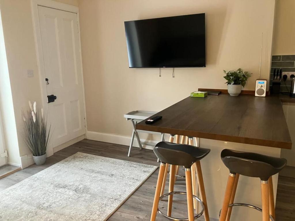 uma sala de estar com uma mesa com bancos e uma televisão na parede em St Andrews - 5 min walk to centre em St. Andrews