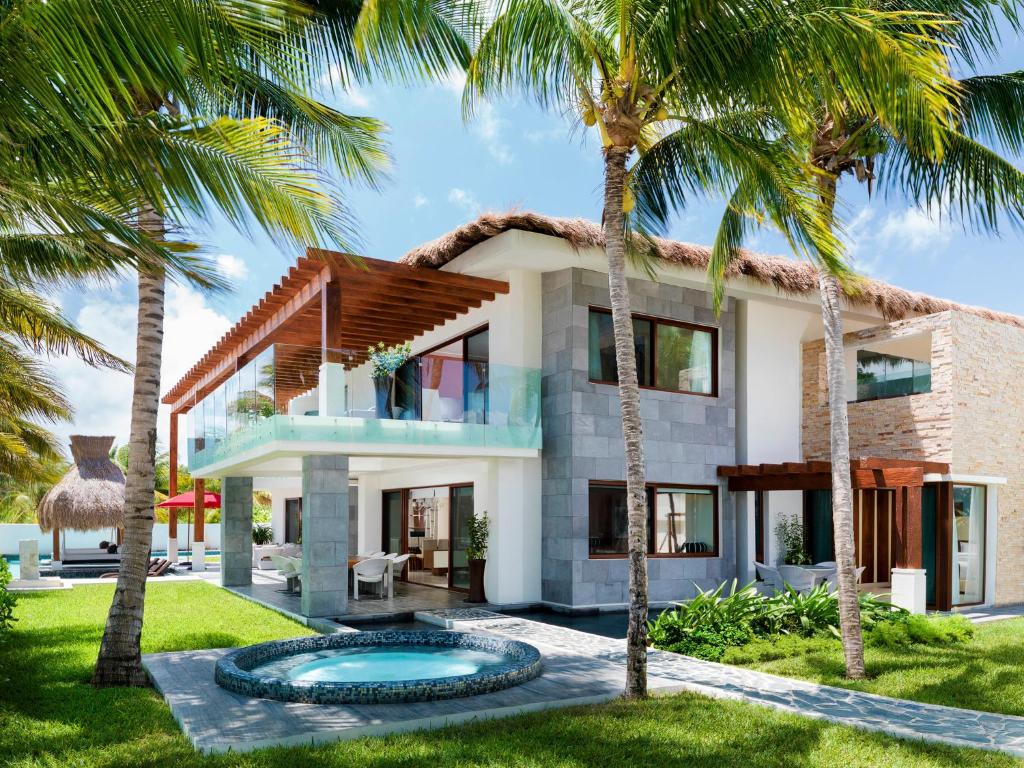 a house with palm trees in front of it at Azul Villa Esmeralda - Gourmet All Inclusive by Karisma in Puerto Morelos