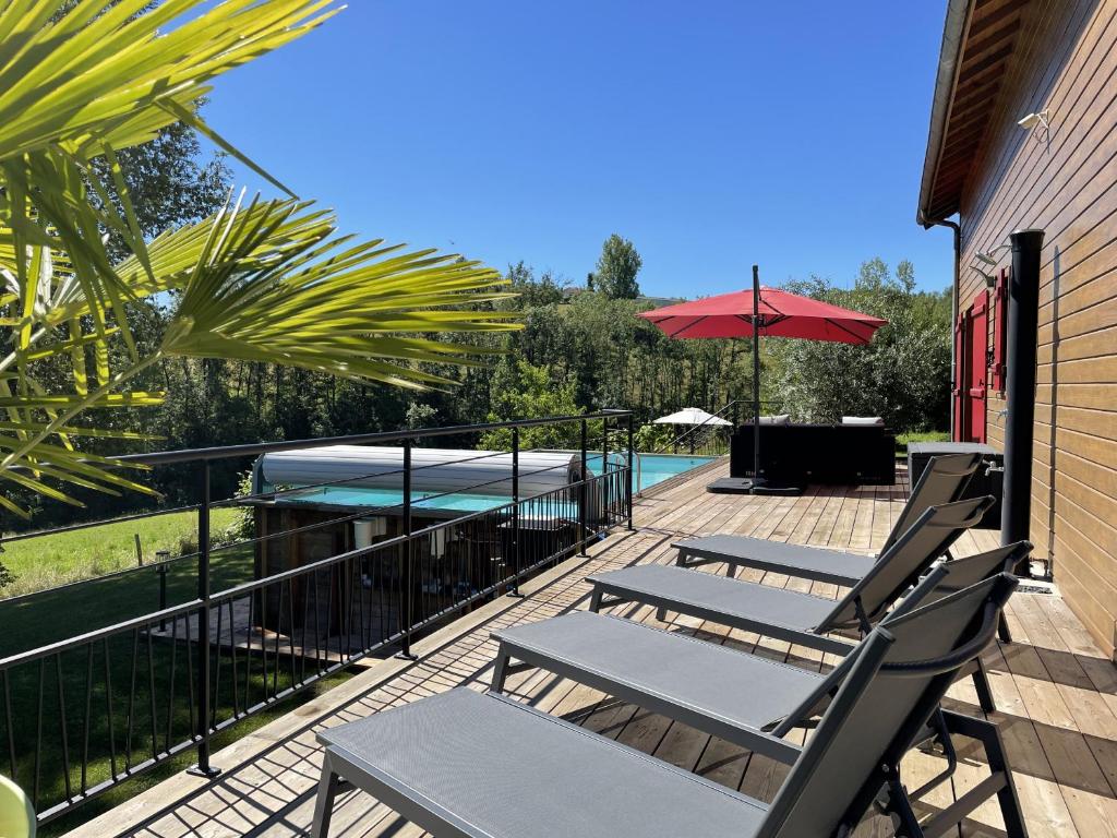 eine Terrasse mit Stühlen, einem Sonnenschirm und einem Pool in der Unterkunft La Manou, esprit bois avec piscine privee in Saint-Aulaire