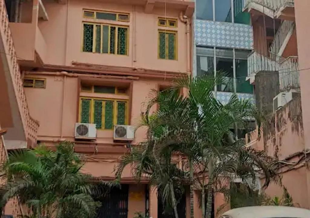a pink building with two windows and palm trees at Hotel Chanderlok Odisha in Rourkela