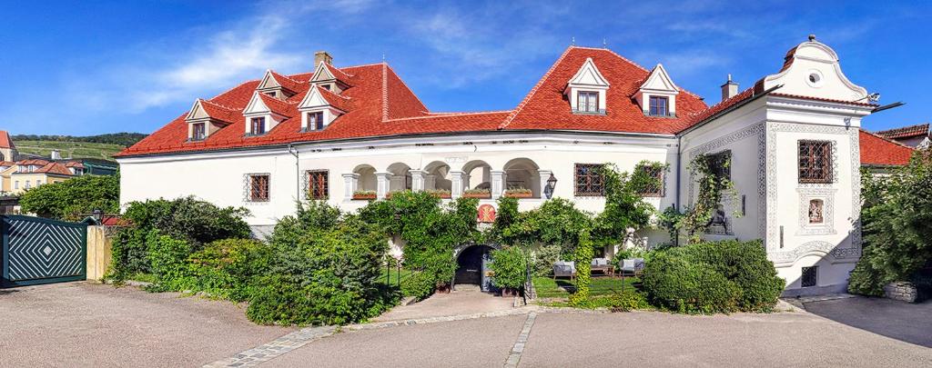 a large white house with a red roof at Renaissancehotel Raffelsberger Hof B&B in Weissenkirchen in der Wachau