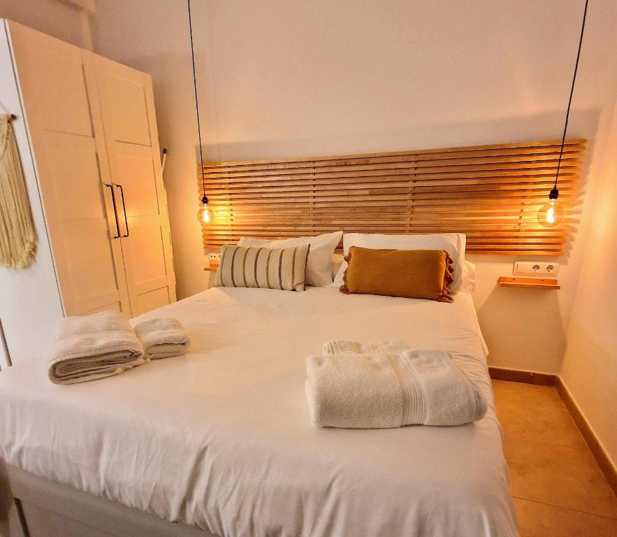 - une chambre avec un grand lit blanc et des serviettes dans l'établissement Loft acogedor cerca de Barcelona, à Terrassa