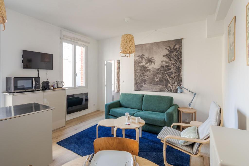 uma sala de estar com um sofá verde e uma mesa em Les Carmélites - Appartements dans l'hyper-centre de Rennes em Rennes