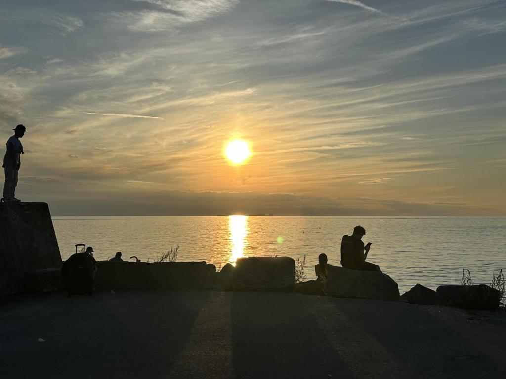 a group of people watching the sunset over the water at Cozy little cottage in the middle of Gotland near Visby in Visby