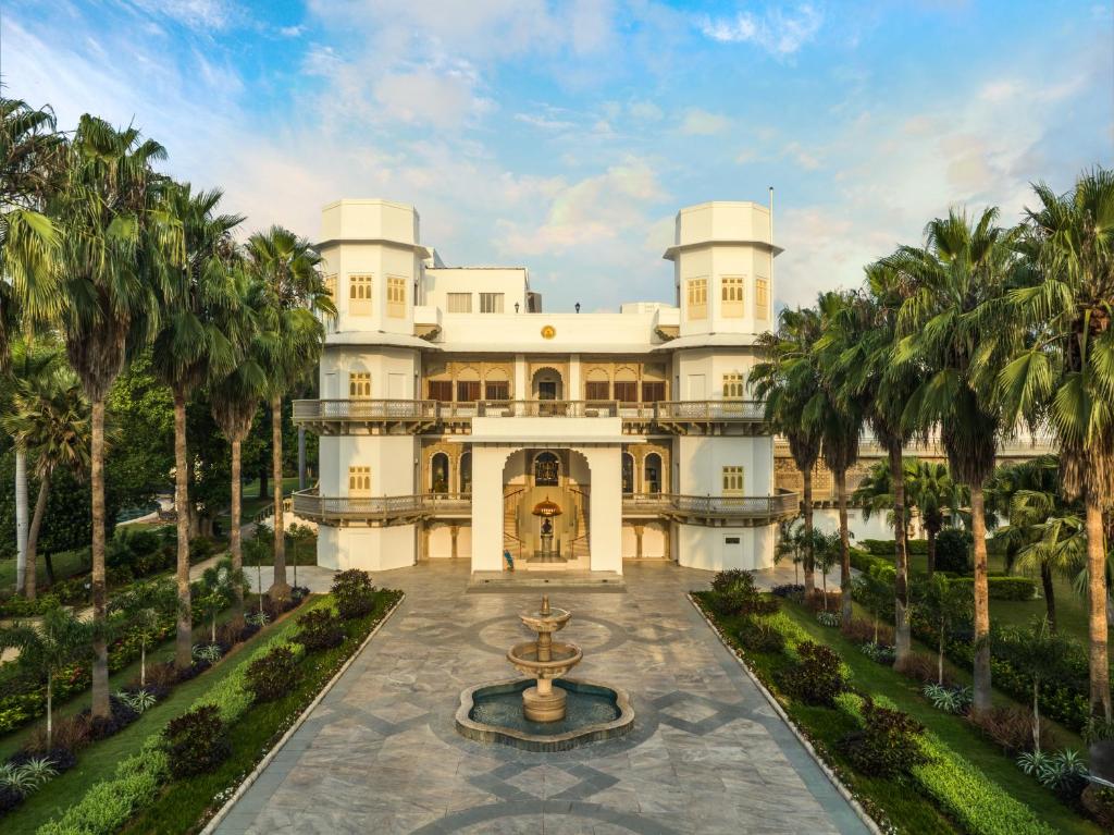 einen Außenblick auf ein großes weißes Herrenhaus mit einem Brunnen in der Unterkunft Taj Usha Kiran Palace, Gwalior in Gwalior