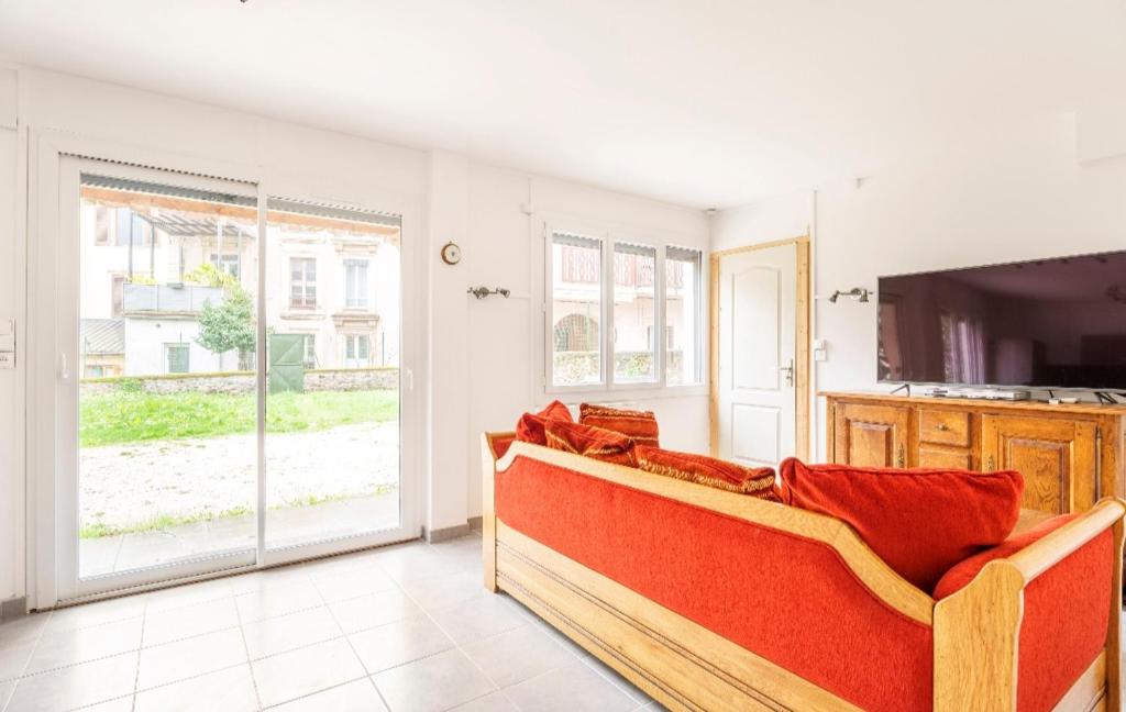 un salon avec un canapé rouge et une télévision dans l'établissement Familial avec jardin privé, à Allevard