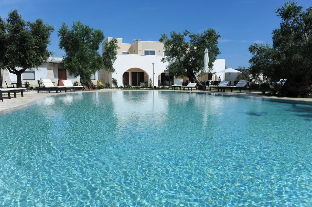 une grande piscine d'eau bleue en face d'une maison dans l'établissement Isola Verde Agriturismo, à Carovigno