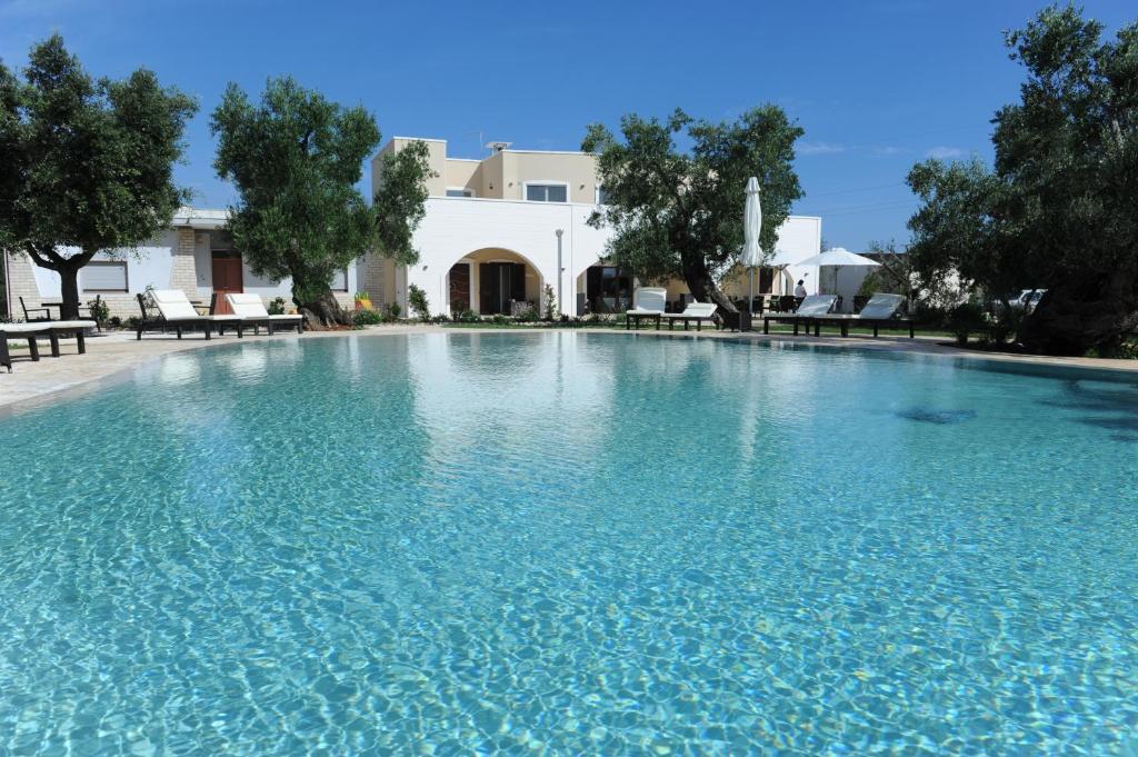 una grande piscina con acqua blu di fronte a una casa di Isola Verde Agriturismo a Carovigno