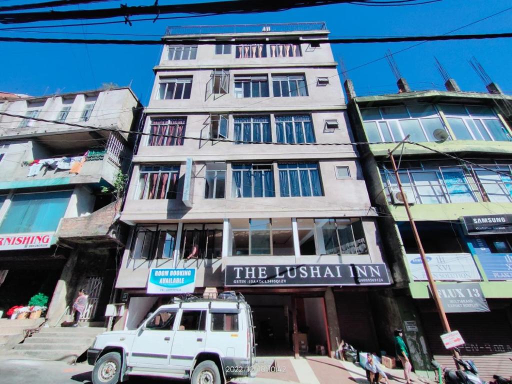 a white truck parked in front of a tall building at The Lushai Inn, Aizwal in Āīzawl