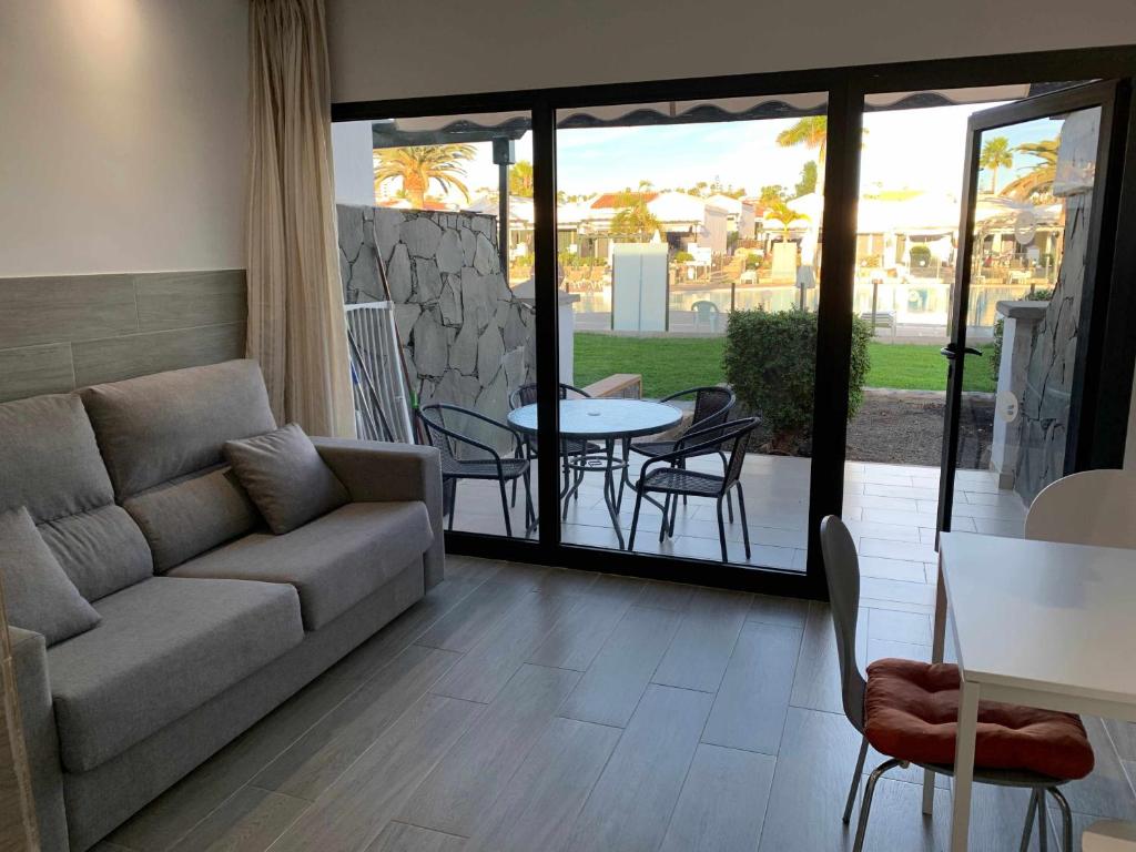 a living room with a couch and a table and chairs at Bungalow enfrente piscina en Maspalomas in Maspalomas