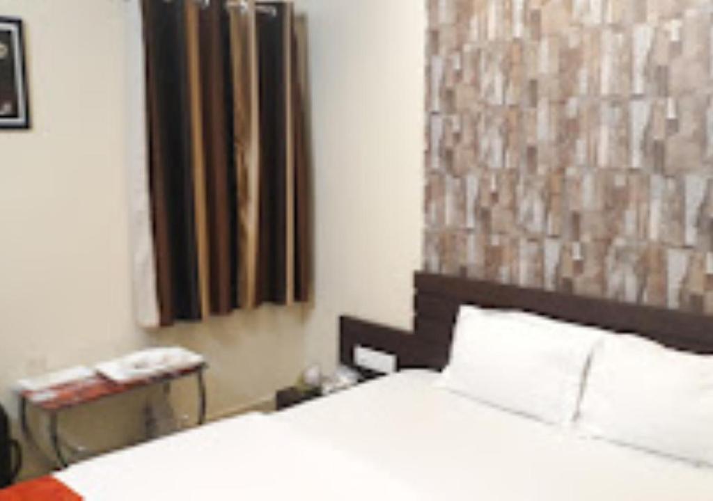 1 dormitorio con 1 cama blanca y teléfono en Hotel Basera Odisha, en Rourkela