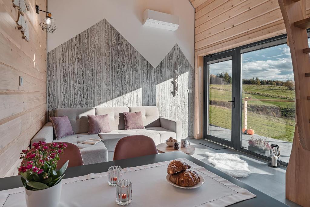 ein Wohnzimmer mit einem Sofa und einem Tisch in der Unterkunft Górski Horyzont - domki nad jeziorem z widokiem na Tatry in Kluszkowce