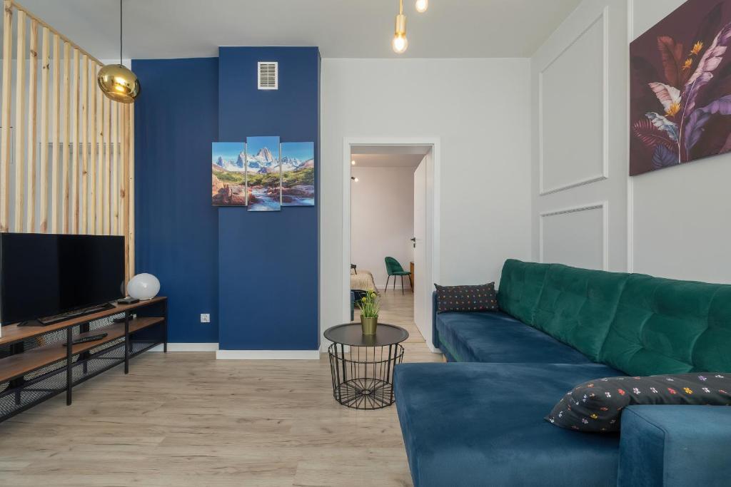 ein Wohnzimmer mit einem blauen Sofa und einem TV in der Unterkunft Kraków Spacious Apartment near Cardiology Clinic by Renters in Krakau