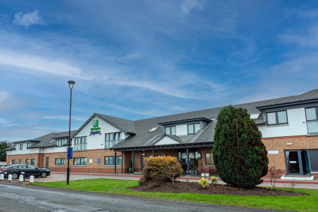 a building with a tree in front of it at Holiday Inn Express Edinburgh Airport, an IHG Hotel in Ingliston
