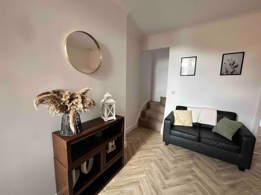 a living room with a black couch and a mirror at 74 Ashby House 3 bed townhouse in Brumby