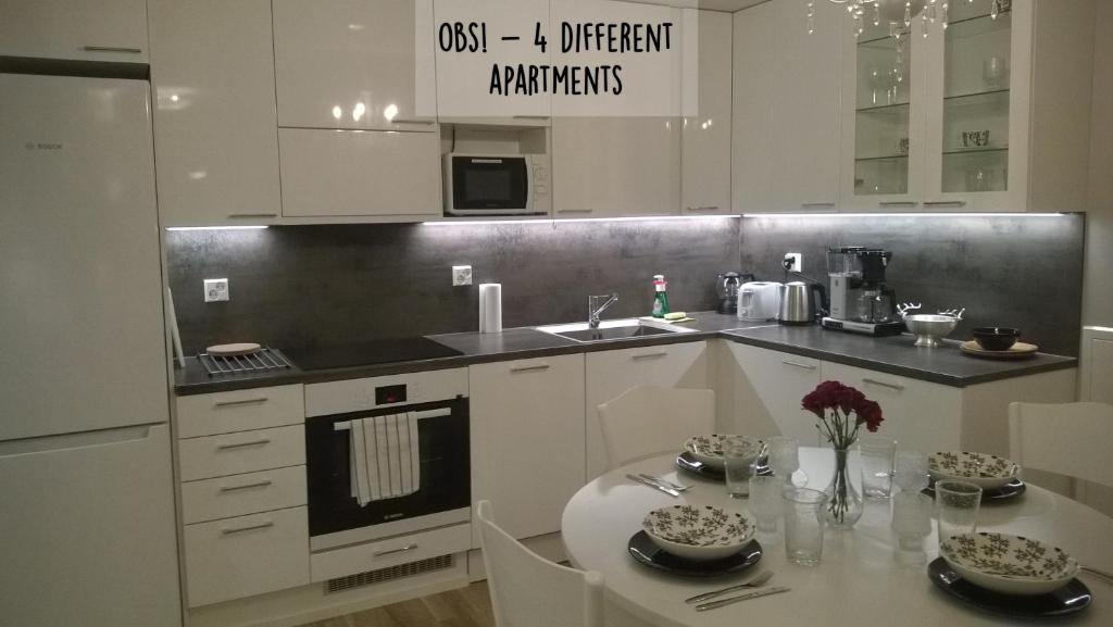 uma cozinha com armários brancos, uma mesa e um lavatório em Piriko Apartments em Rovaniemi