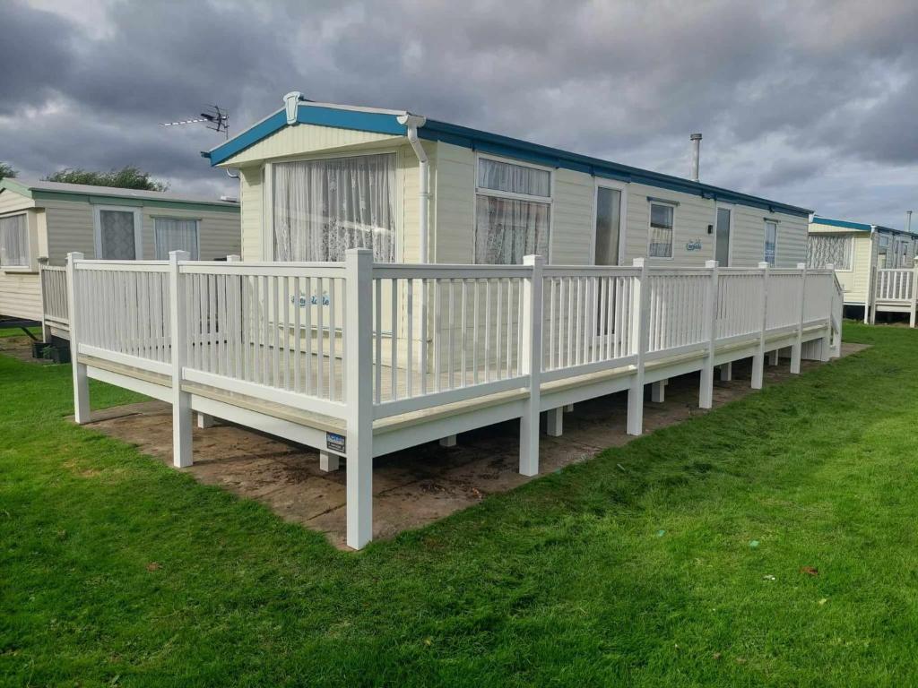 a row of mobile homes with a white fence at 8 BERTH CARAVAN TP49 ON THE GOLDEN PALM CHAPEL ST LEONARDS in Skegness