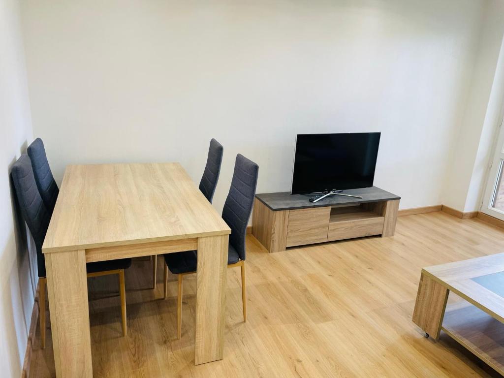 a dining room table with chairs and a television at Jolie T3 à Colomiers in Colomiers