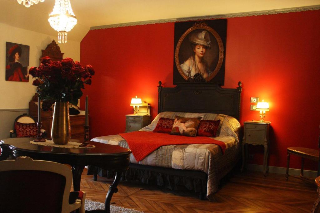 a red bedroom with a bed with a painting on the wall at Le Bonheur à la Campagne in Lesmont