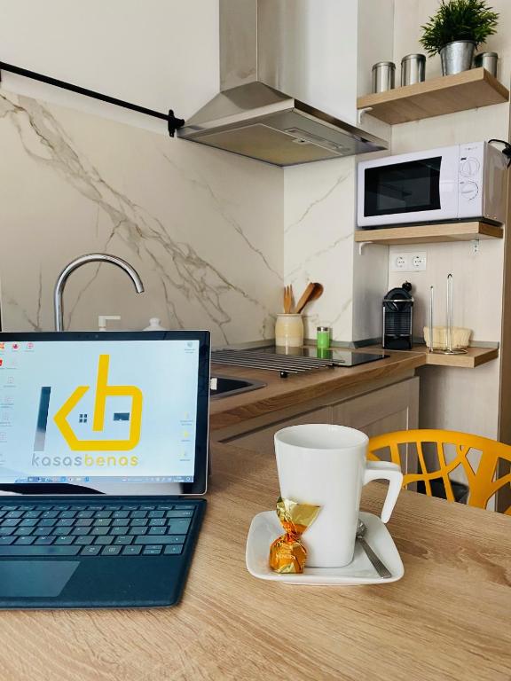 贝纳斯克Apartamento Netu - kasasbenas的坐在木桌旁的笔记本电脑,喝杯咖啡