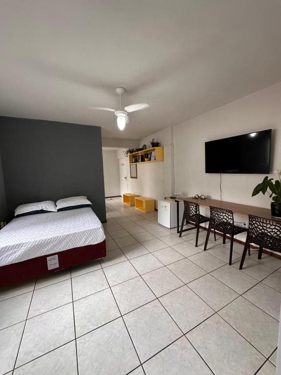 Schlafzimmer mit einem Bett und einem Flachbild-TV in der Unterkunft Quarto próximo à praia in Balneário Camboriú