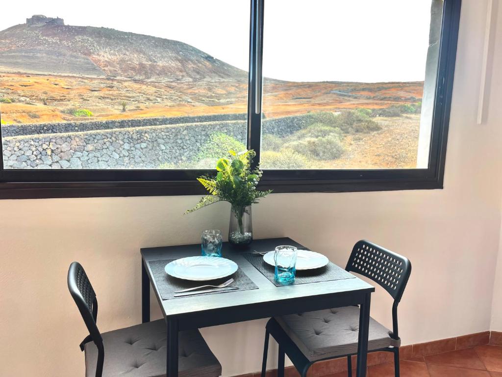 a table and chairs in a room with a large window at Apartamento Guanapay by Vulcano Homes in Teguise